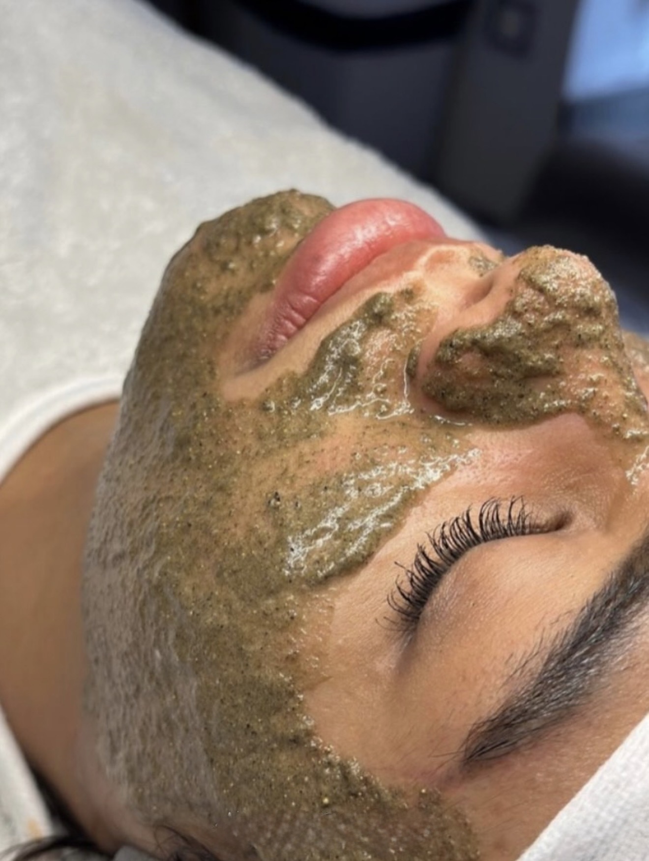 Client relaxing with a green enzyme treatment mask applied during a customised facial